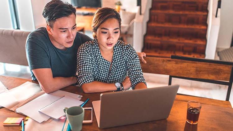 Couple figuring out a budget breakdown on their laptop.